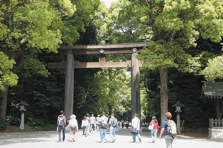 明治神宮の木造の大鳥居と参道を歩く人々