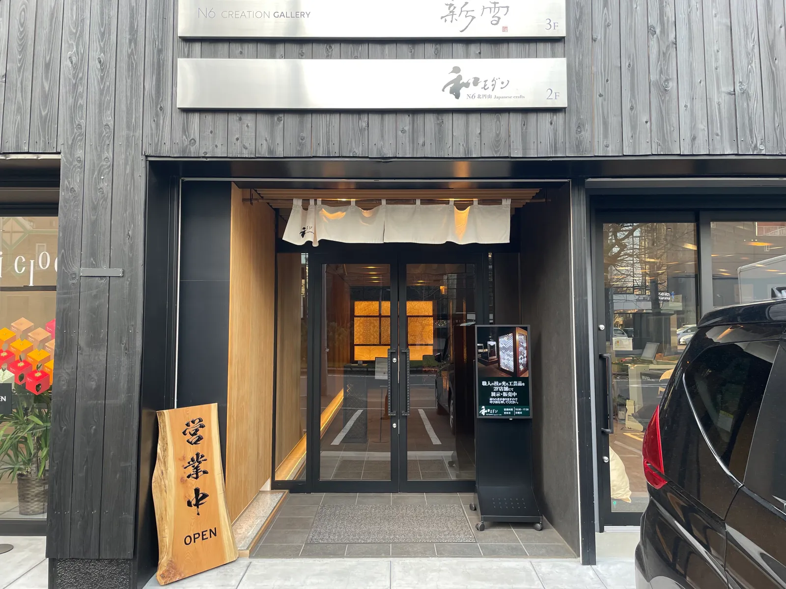 暖簾が掛かった入口と「営業中 OPEN」の木製看板