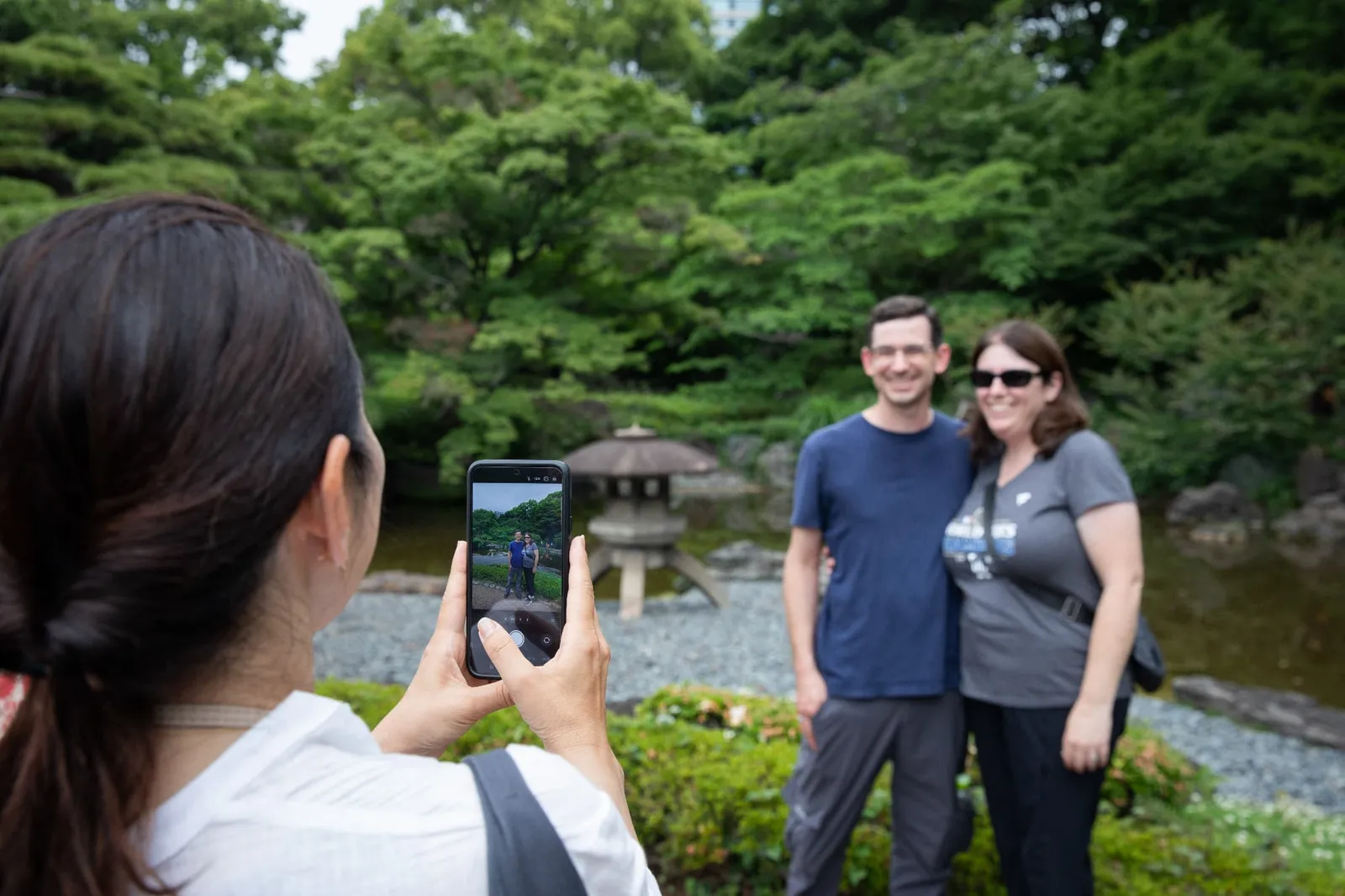 灯籠のある池の前で写真を撮られる二人