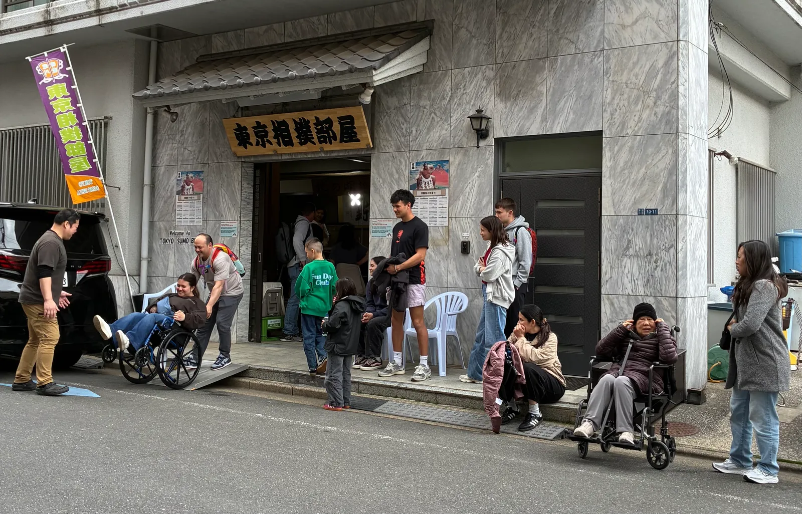 東京相撲部屋の入口に集まる参加者と車椅子利用者