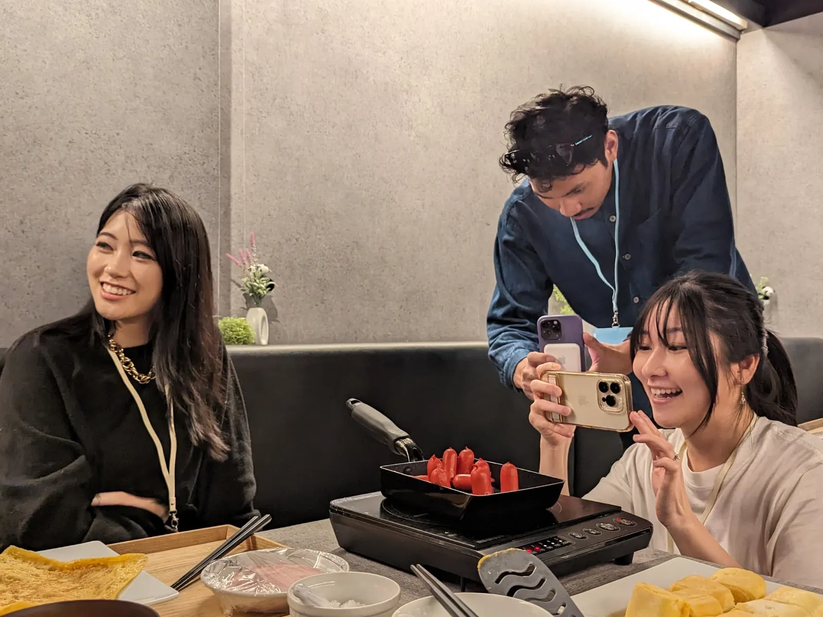 卓上IHと卵焼き器でウインナーを焼く参加者を講師がスマートフォンで撮影する様子