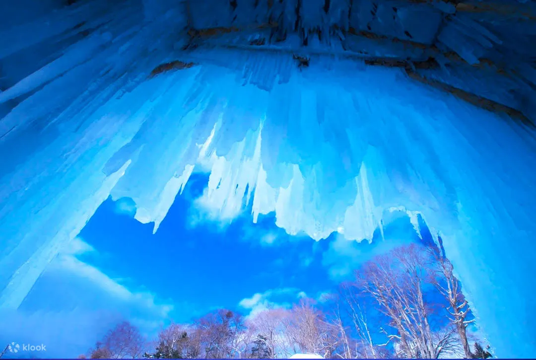 氷のトンネル内から見上げたつららと青空