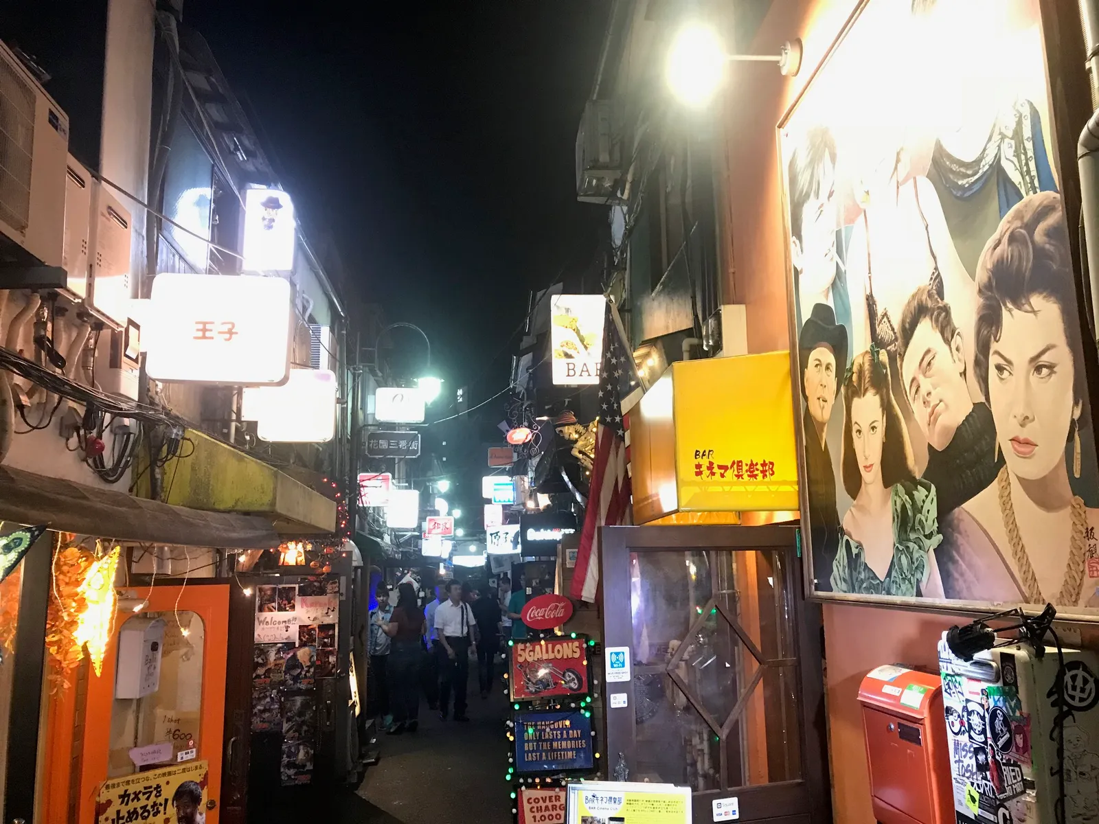 映画風の壁画とバーの看板が並ぶ路地