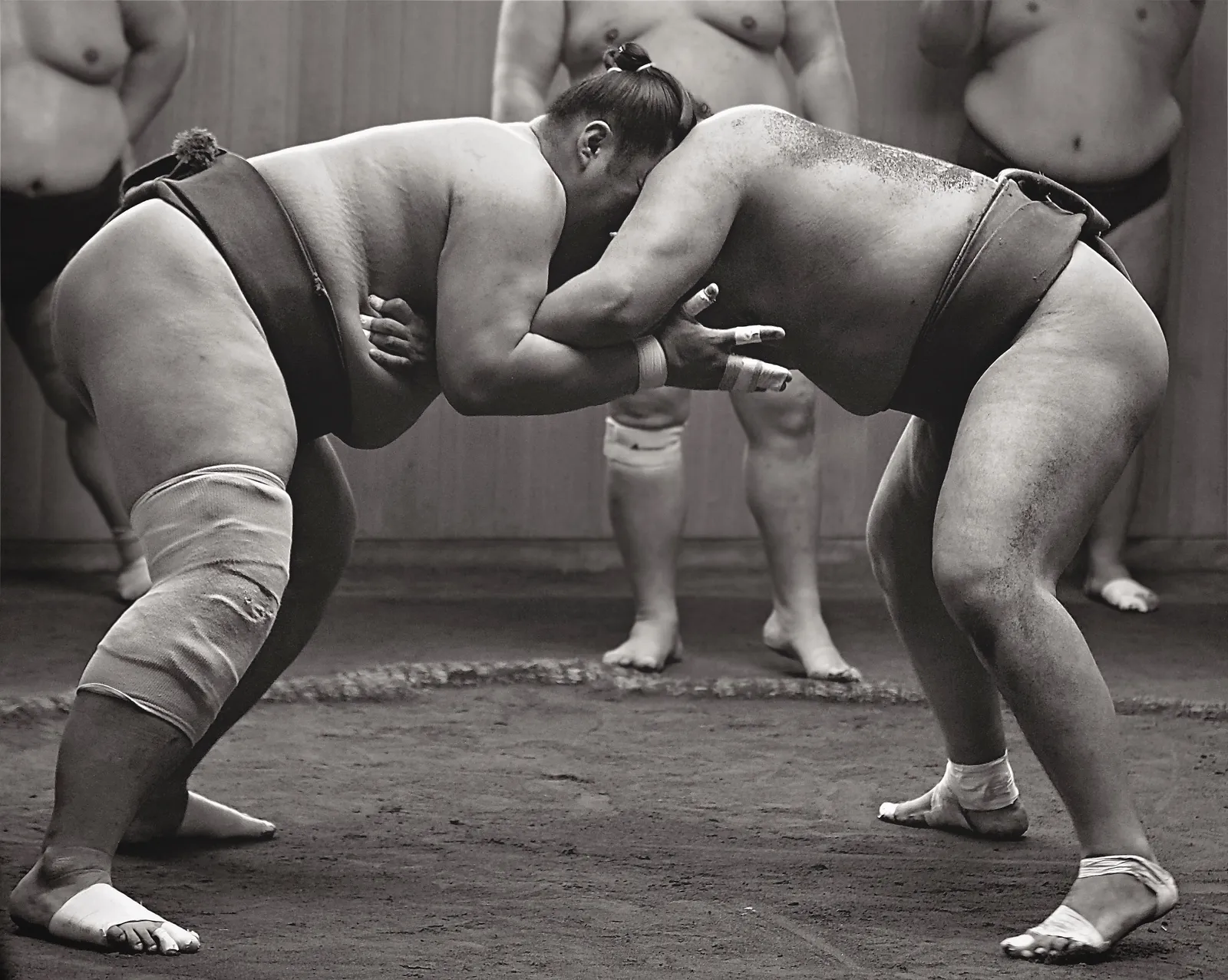 土俵で組み合う2人の力士を写したモノクロ写真