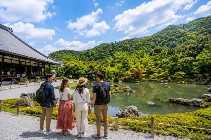 池と山の緑を眺める4人の参加者と、天龍寺の庭園