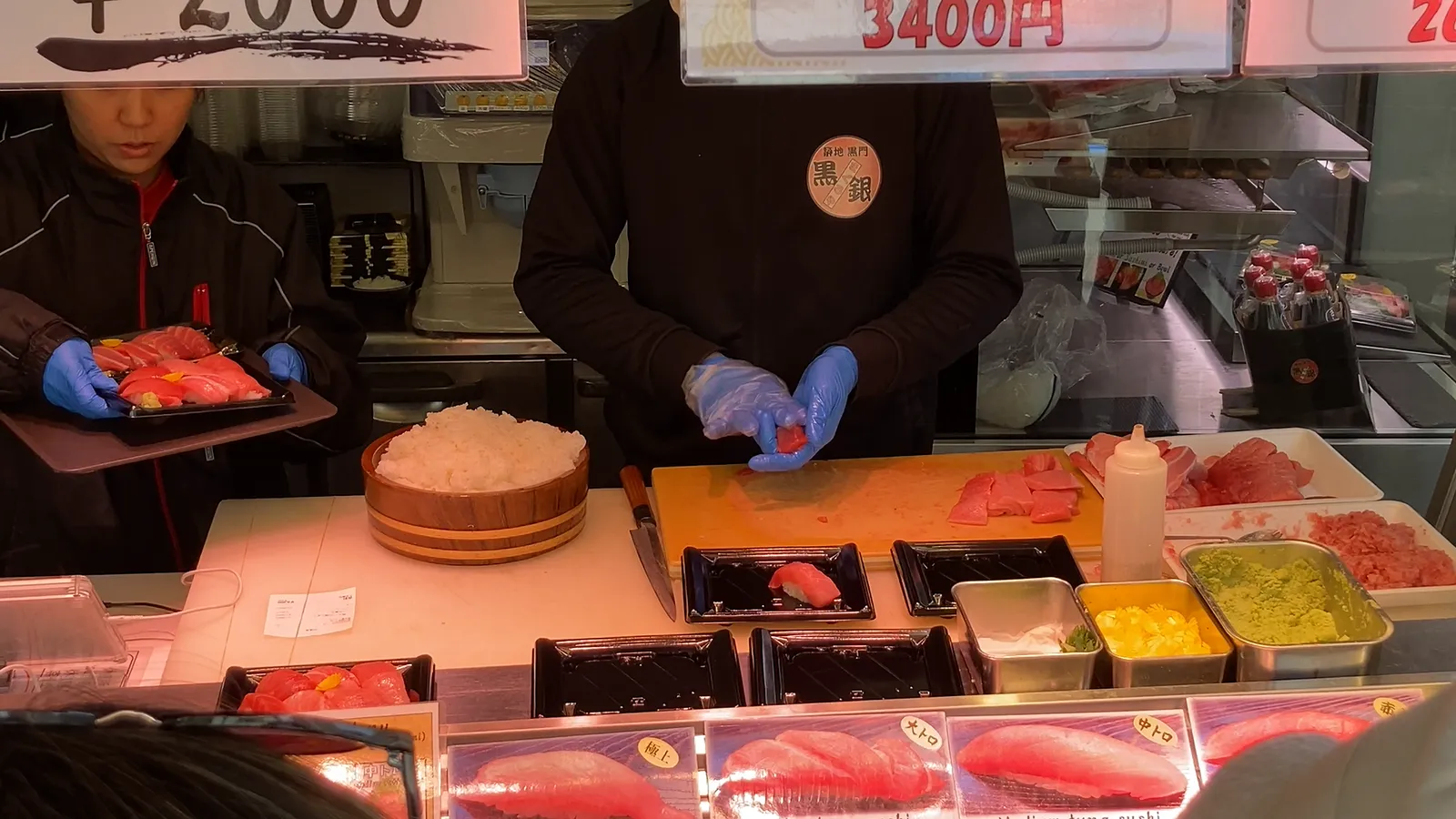 유리창 너머로 참치 스시를 쥐는 장인과 진열장