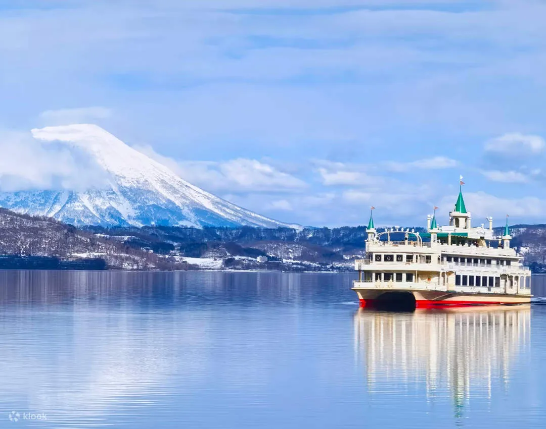 雪の羊蹄山を背に湖を進む遊覧船