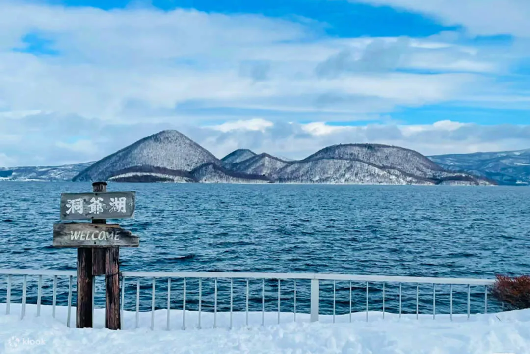 雪の洞爺湖畔に立つ「洞爺湖 WELCOME」の看板と中島